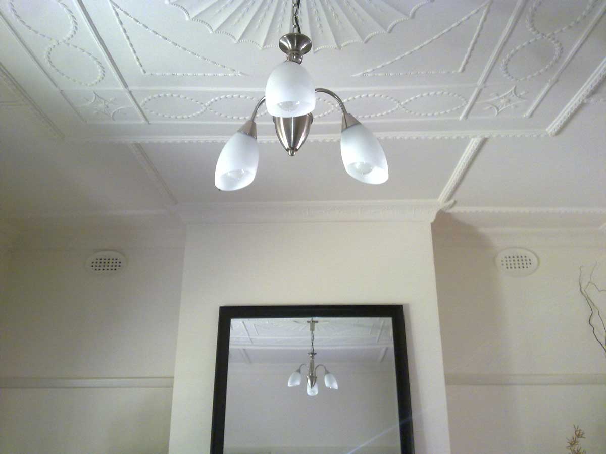 Restored ornate white pressed ceiling with pendant light and cornice