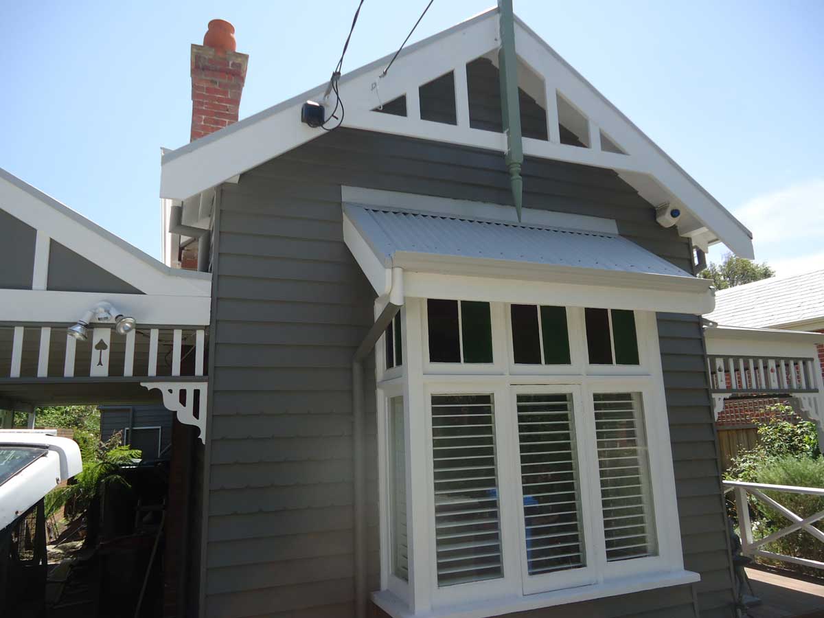 Grey weatherboard cottage gable with white trim, freshly painted