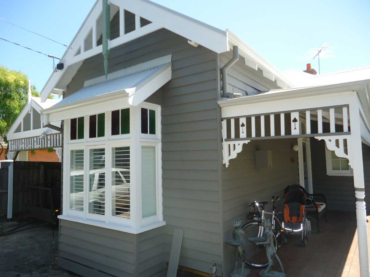 Full grey weatherboard cottage exterior, freshly painted with verandah
