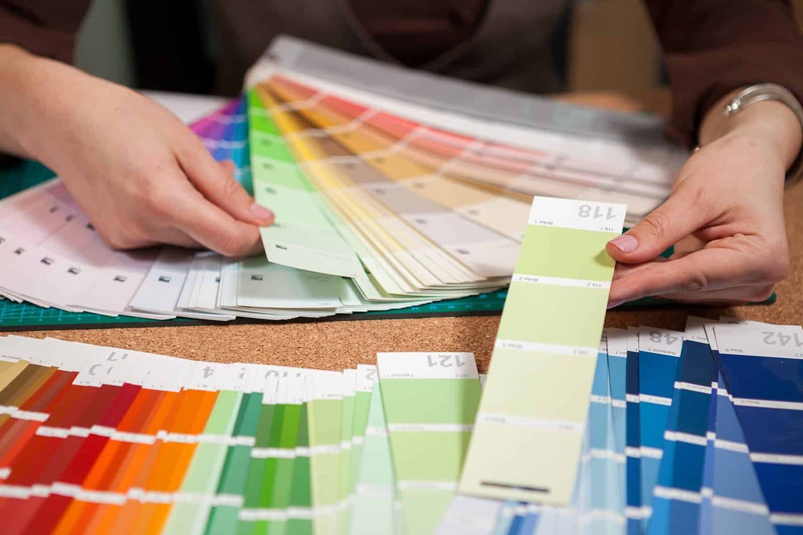 Hand selecting a paint colour from a fanned set of sample swatches